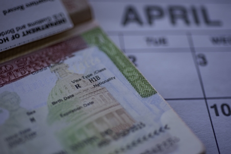 H1B visa (for specialty workers) stamp in passport, blurred april calendar on background